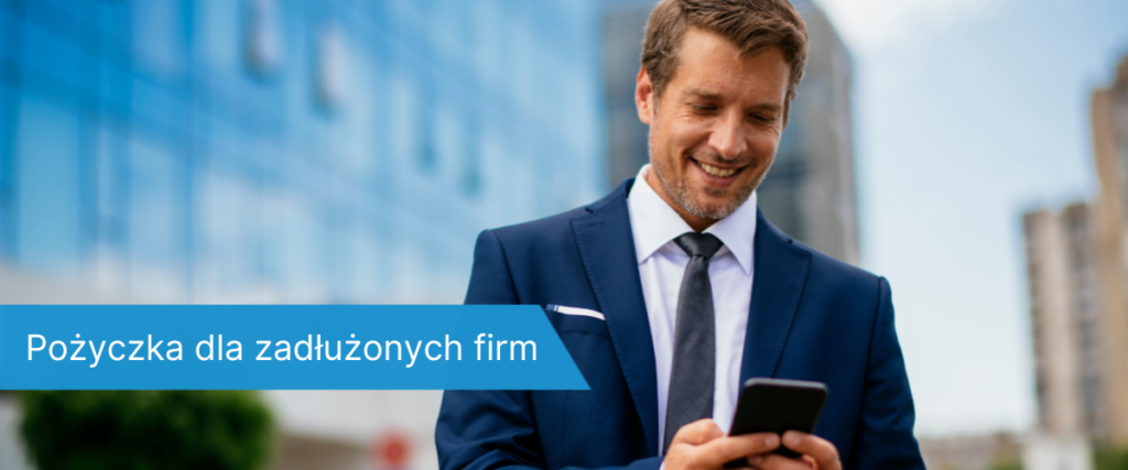 Mężczyzna w garniturze stojący na zewnątrz przed nowoczesnym biurowcem, patrzy z uśmiechem na smartfon