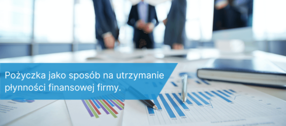 Dokumenty finansowe i wykresy na biurku w biurze, w tle rozmowa biznesowa — symbol utrzymania płynności finansowej firmy dzięki pożyczce.